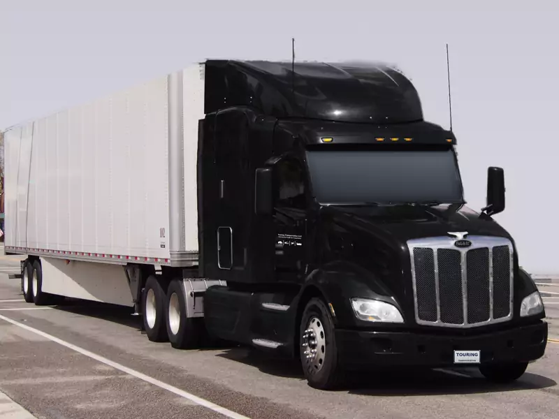 Peterbilt 579 negro con remolque seco de 53 pies y el logo de Touring Transportation en la puerta
